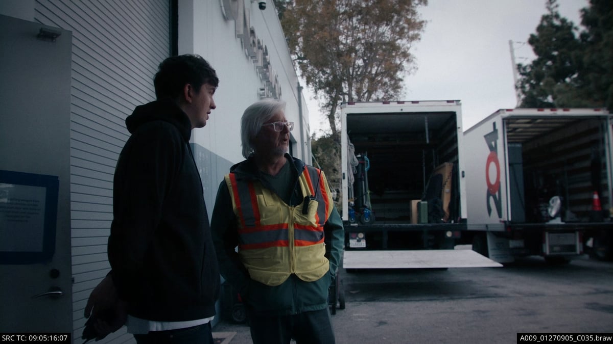Production staff and a man wearing a reflective safety vest engaged in a discussion.