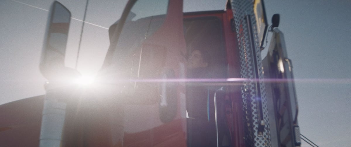 A woman opening the truck door and stepping out, with sunlight at her back casting a reflective glow on the front