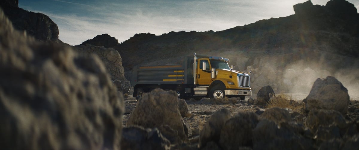 A magnificent large yellow truck amidst a rugged rocky landscape.