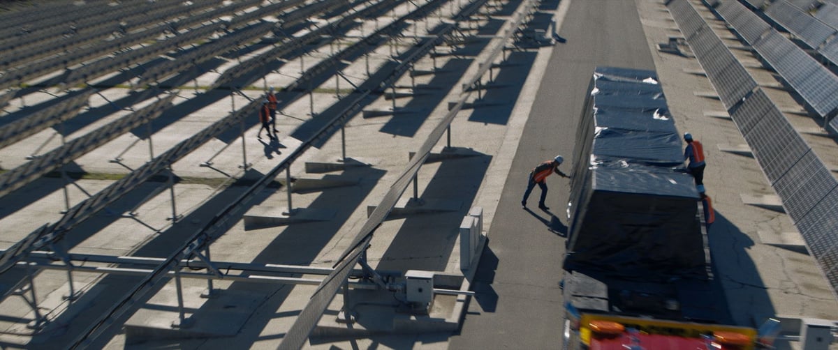  Two crew members on-site filling a truck amidst a large lineup of solar panels