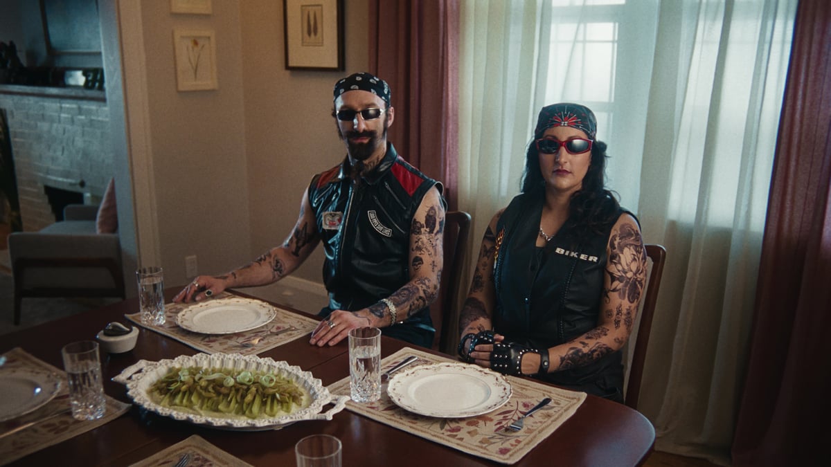 Couple seated at the dining table, dressed like rockstar bikers.