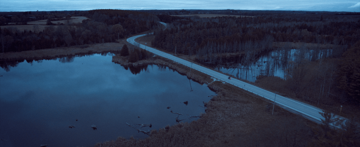 An aerial shot captures the beauty of a stunning lake, adorned with a bridge road that extends to the opposite shore.