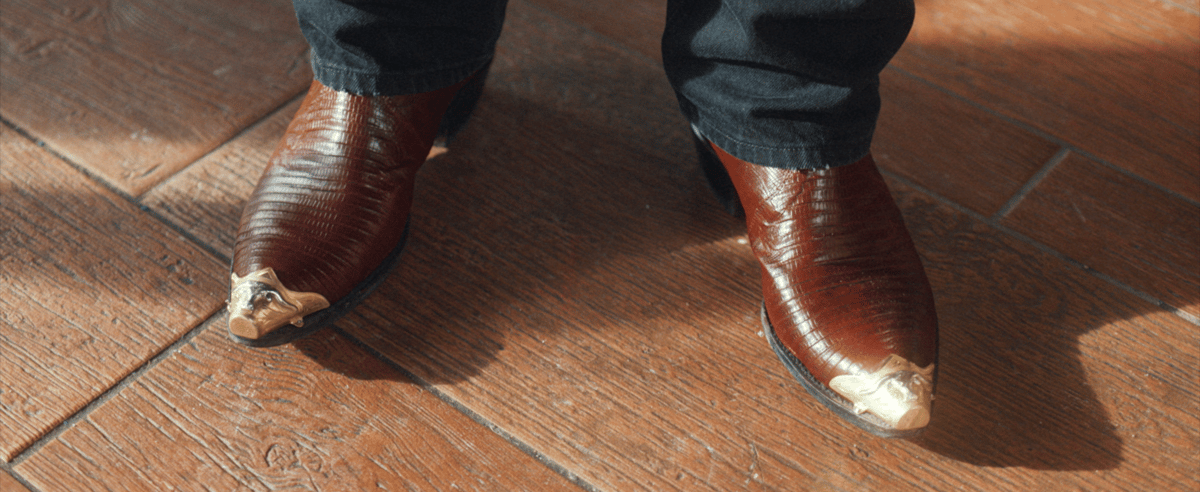 The feet of a man, adorned in a pair of boots with golden tips.