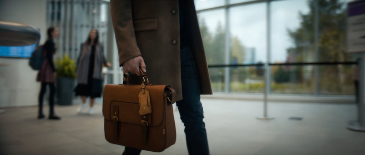 A man walking while carrying a brown bag.