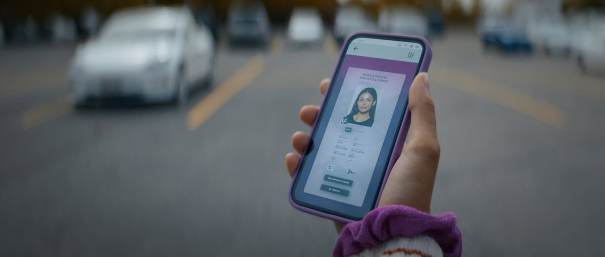 A woman's hand holding a mobile device, displaying her identity on the app.