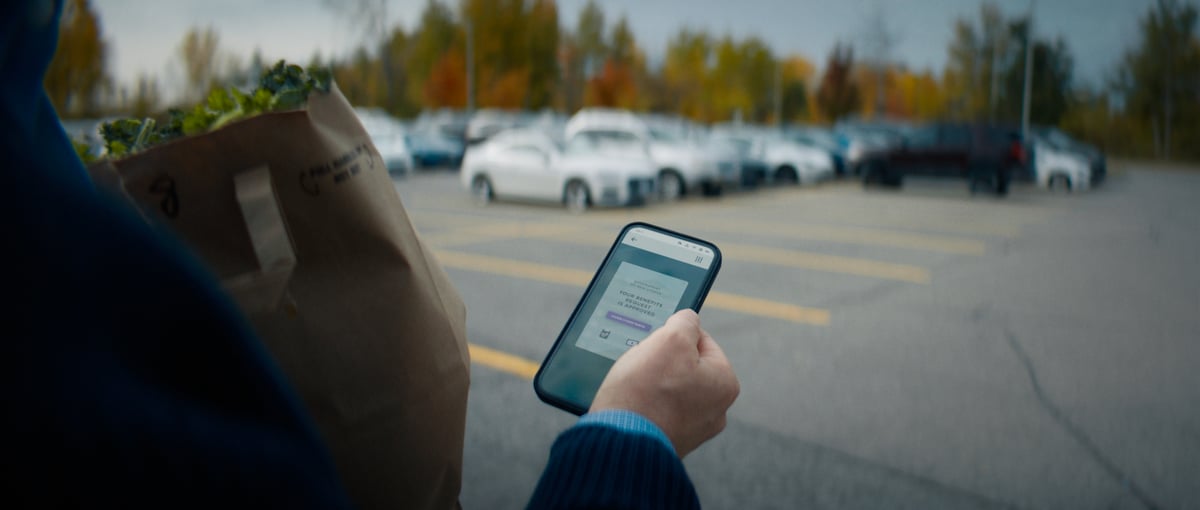 The hand of the older man holding his mobile device, displaying the app.