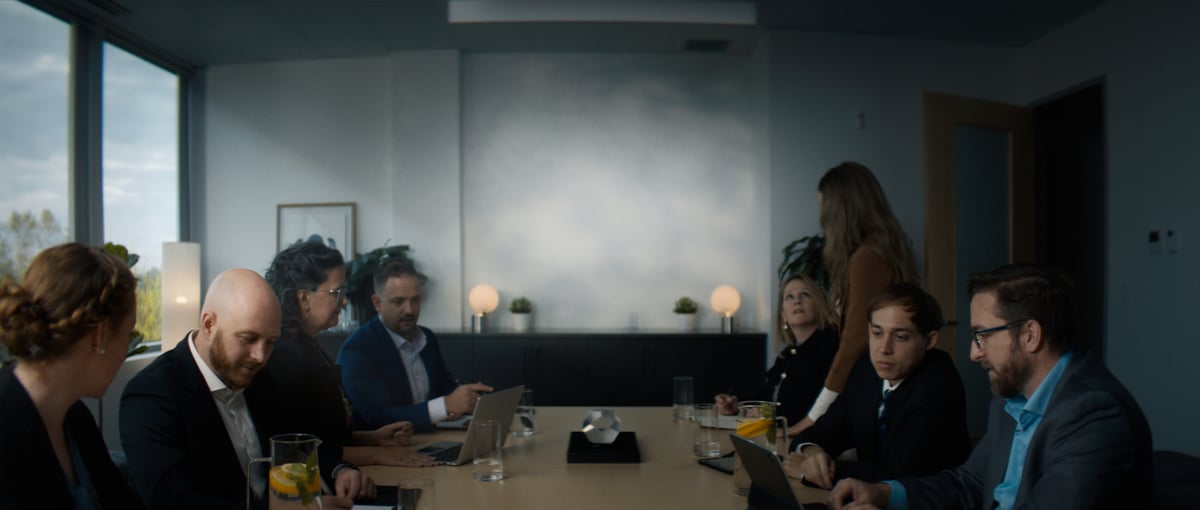 The team gathers around a desk for a meeting.