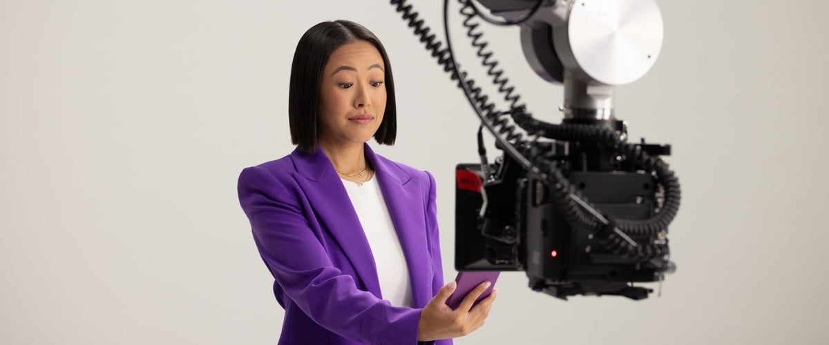 The woman holds her mobile phone in front of a video camera .