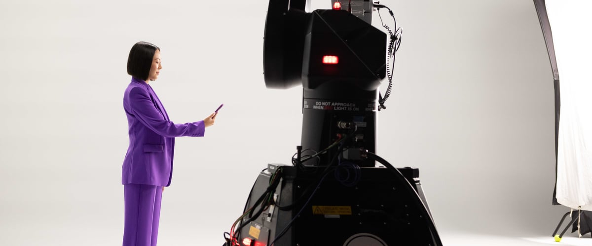 A woman stands upright, holding her mobile phone on the set.