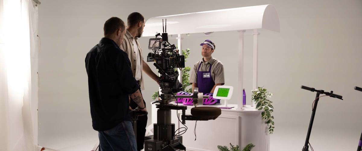 The cameramen are in discussion, providing instructions to the actor who portrays the booth attendant.