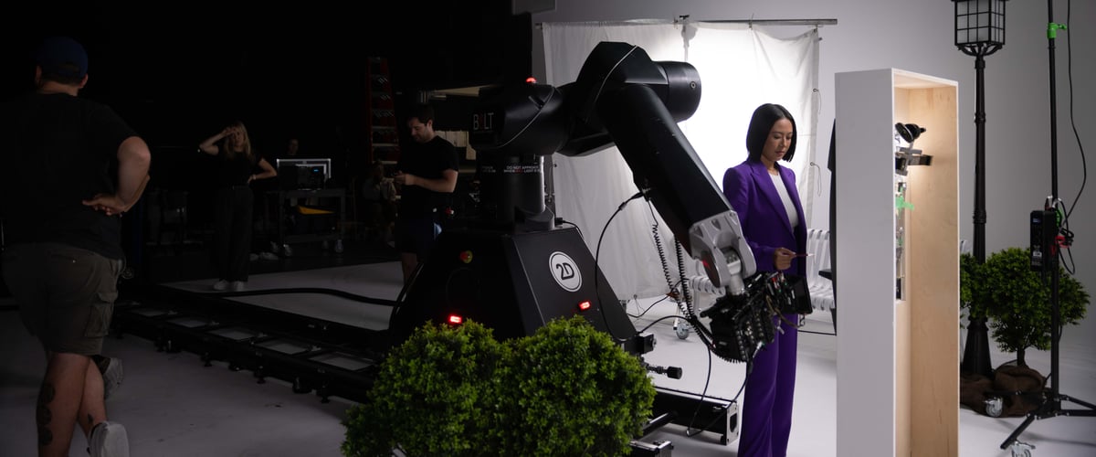 The actress is on the set, in front of the ATM machine, while the camera captures the scene.