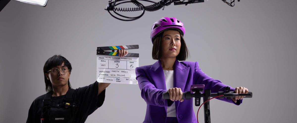 The actress is on set in a scene where she is riding a scooter, with a man behind her holding the clapperboard, ready to signal the start of the take.