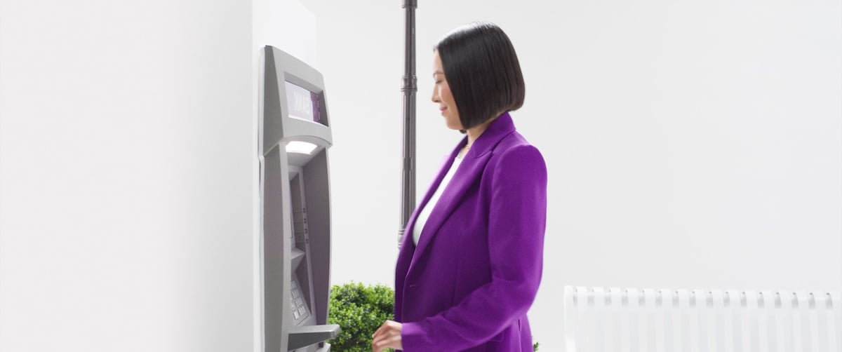 A woman stands in front of the ATM machine.