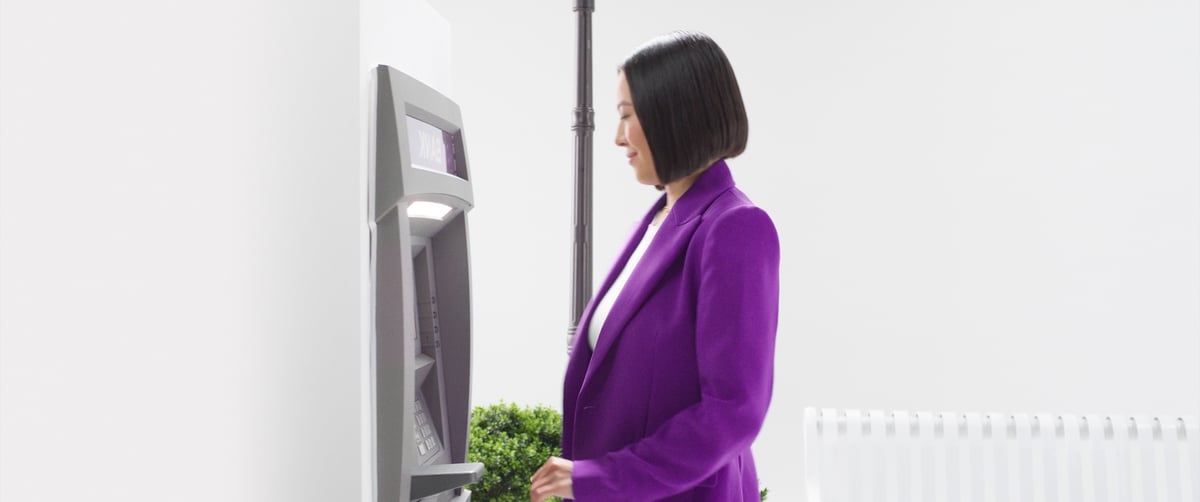 A woman stands in front of the ATM machine.