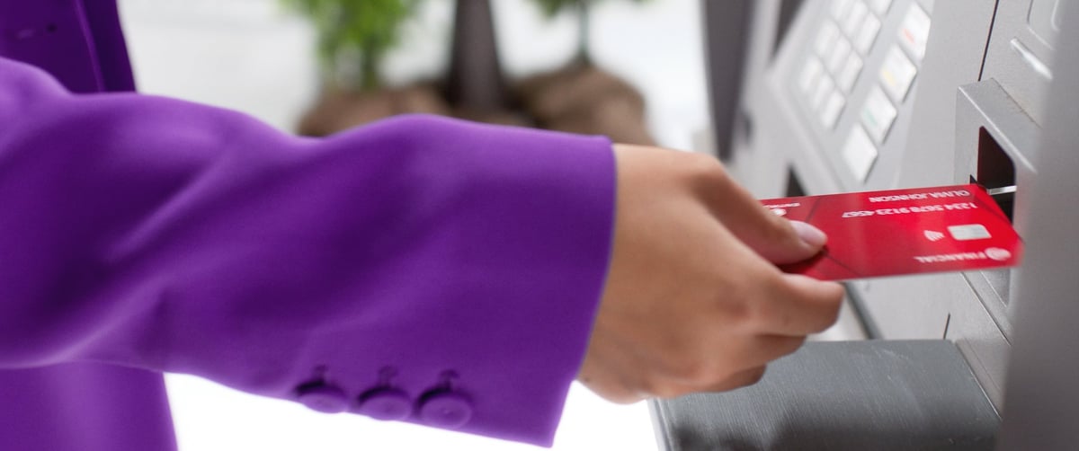The woman's hands insert a card into the ATM machine.