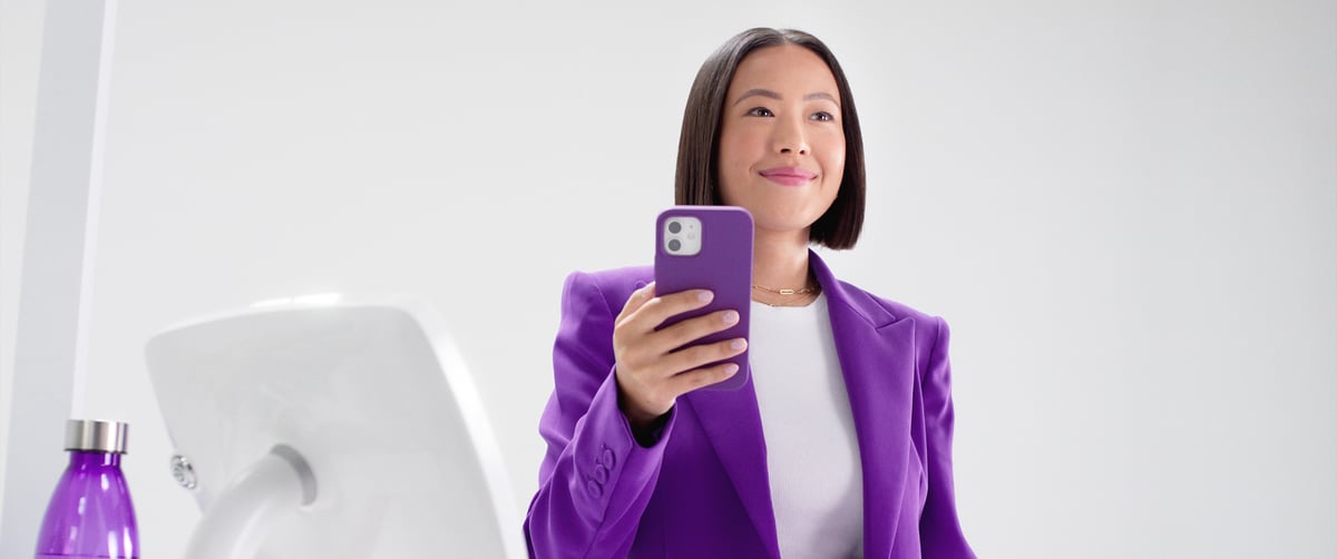 The woman smiles confidently, holding her phone, ready to make a payment through the scanner.