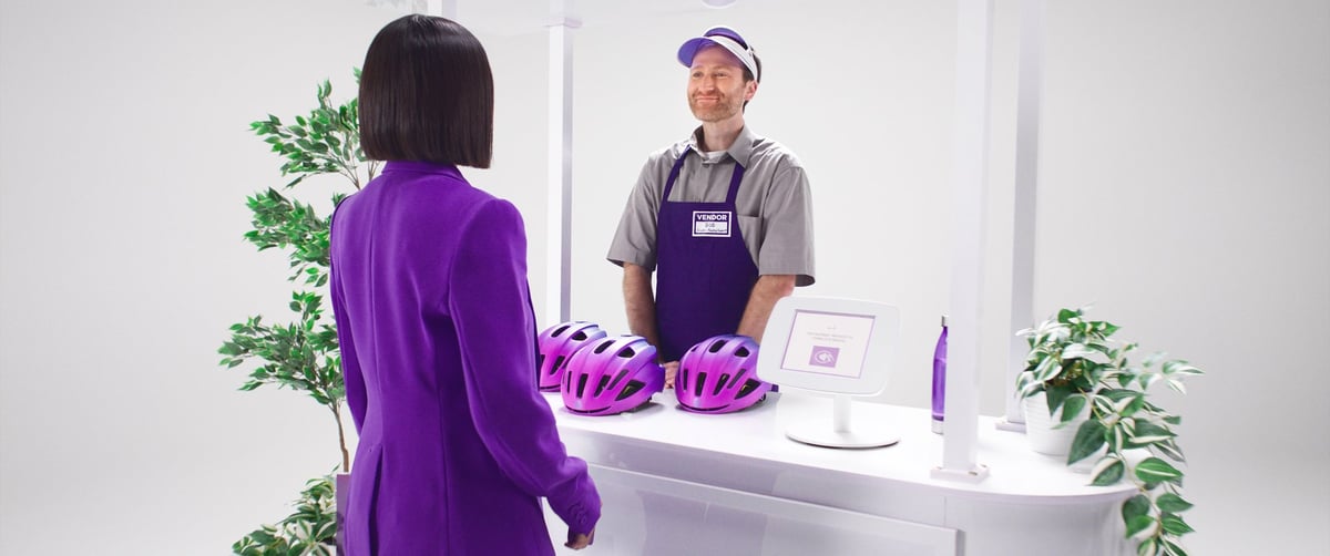 A woman is engaged in conversation with the smiling attendant at the booth.
