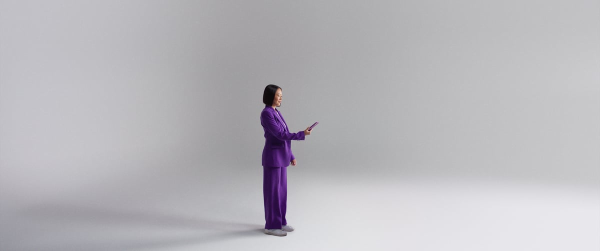 A woman stands upright, holding a mobile phone, dressed in a stylish purple outfit.