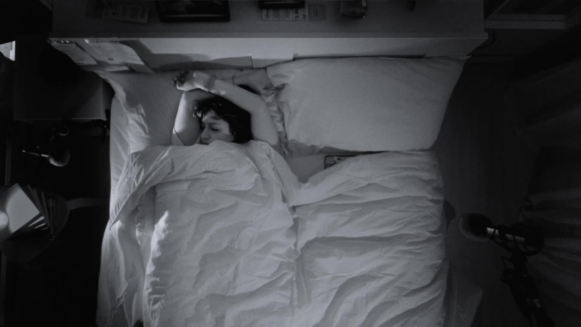 Nestled under white linens, a participant drifts into sleep in a staged IKEA bedroom wired for night audio.
