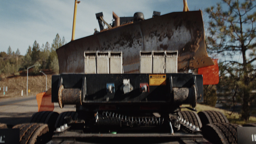 A heavy-duty dozer is secured onto a flatbed trailer, emphasizing the scale and weight of the load being transported.