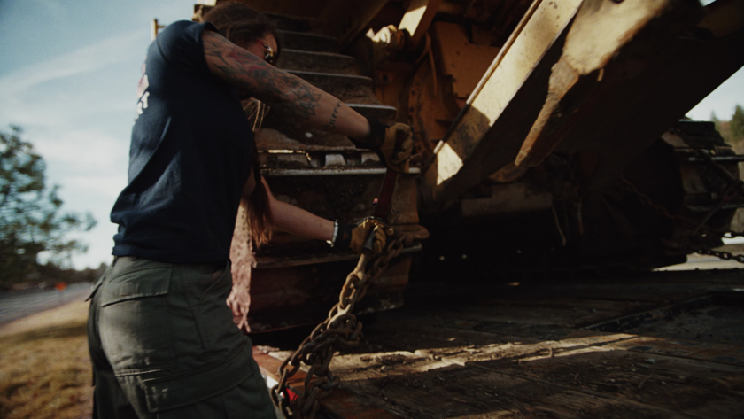 Chains clank and tighten as the driver locks down a massive tracked dozer, highlighting the muscle and care behind every load.