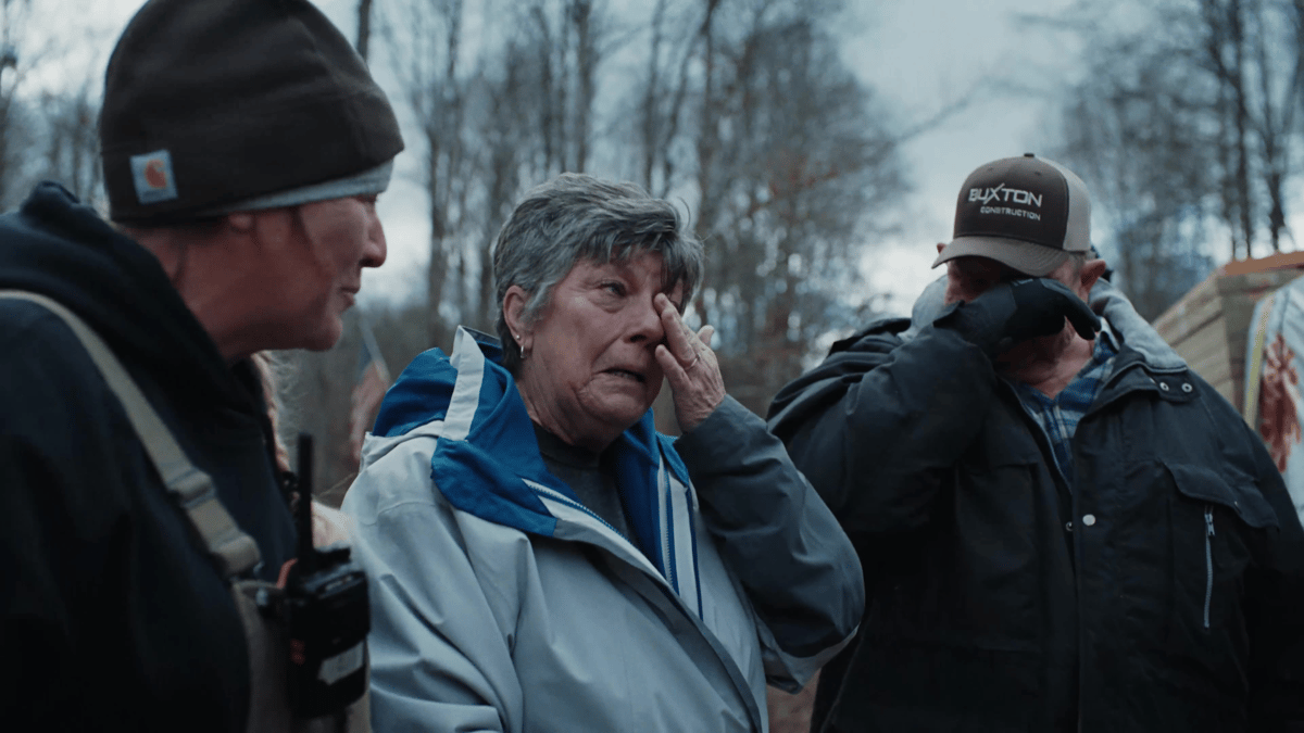 Three community members wipe away tears at the job site, capturing the emotional weight of rebuilding efforts.