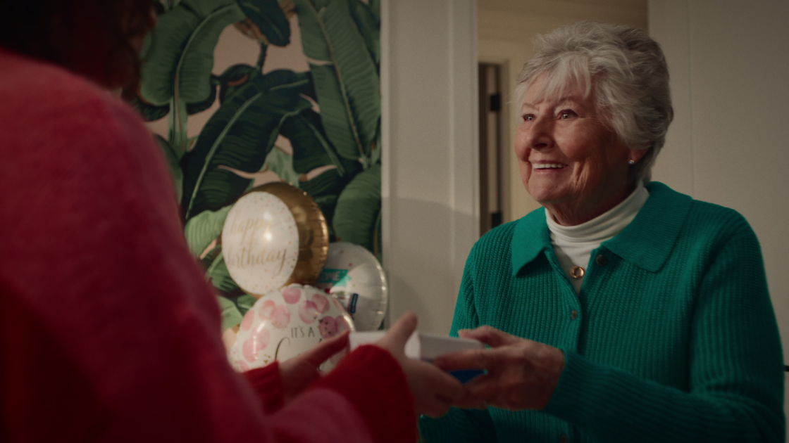 A grandmother handing a Jewlr box to her daughter.