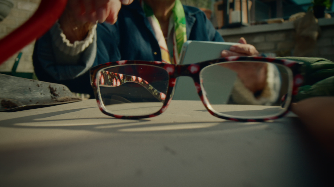 A glass placed on a table as a hand reaches out to pick it up.