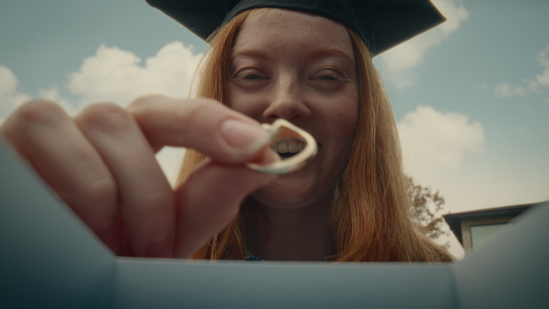 A graduating daughter holding a ring gifted by her father.
