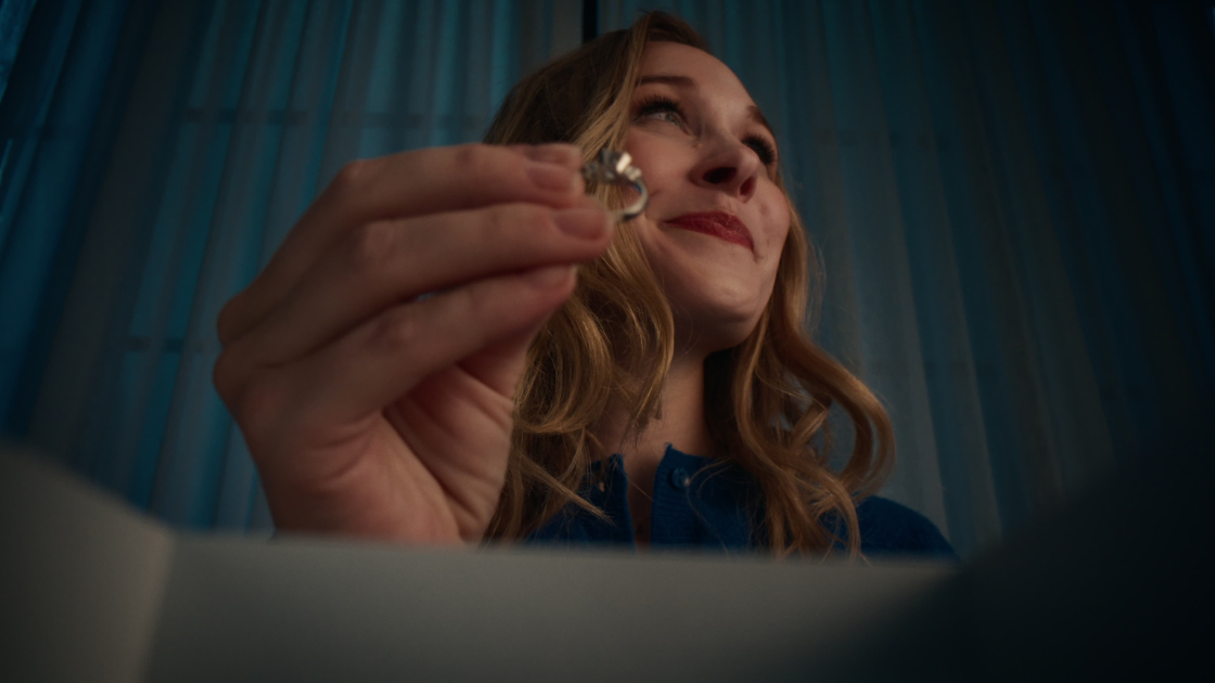 A wife admiring a ring while looking at her husband with deep emotion.