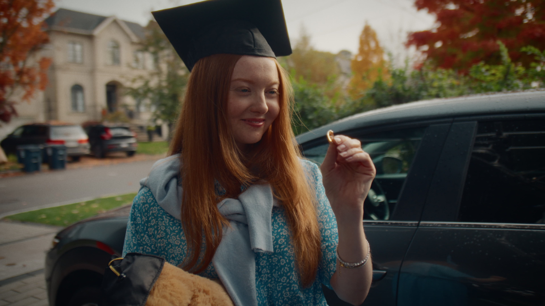 A graduating daughter holding a ring and gazing at it with deep appreciation.