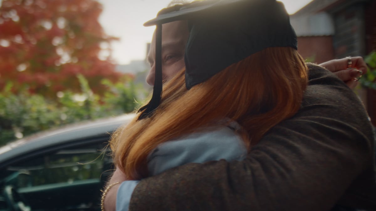 A close-up of a father and daughter hugging, with the daughter holding the ring.