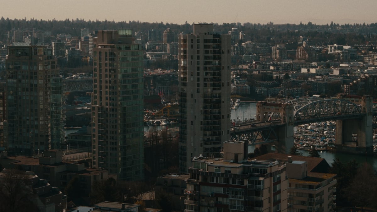 A daytime cityscape of Vancouver showing residential high-rises, the Burrard Street Bridge, and False Creek marina.