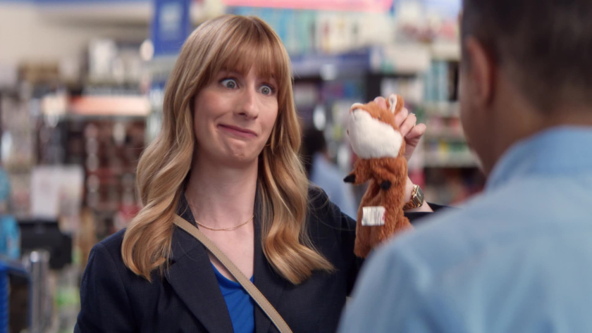 A customer holds up the plush fox with a humorous expression toward the cashier.