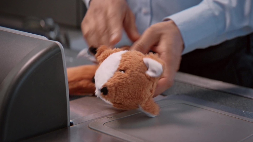Close-up of a cashier scanning a plush fox toy at the checkout.