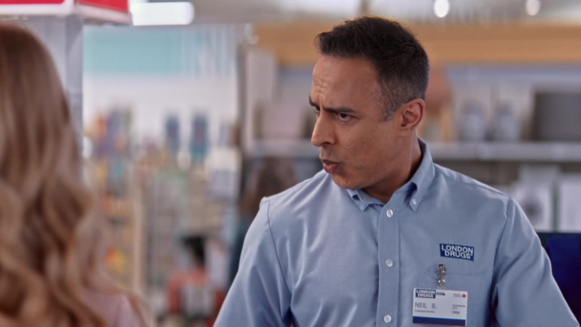 The London Drugs cashier reacts with a surprised expression while speaking to a customer.