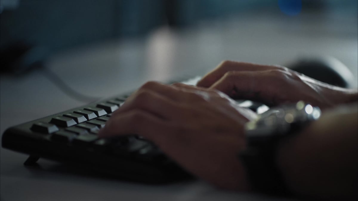 A close-up of hands typing on a keyboard, with a computer mouse visible in the background