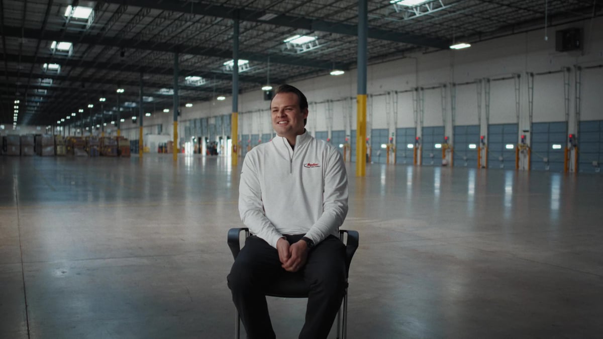 Seth Devlugt sits in a chair inside a large, mostly empty warehouse facility