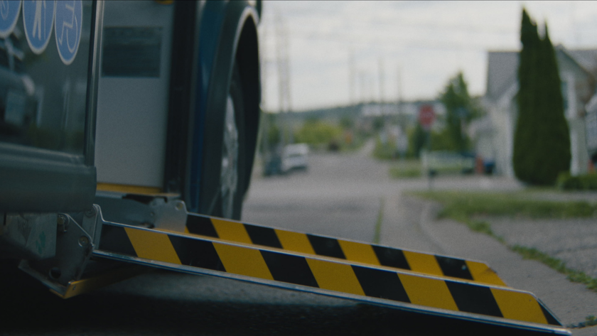 A close-up of the bus’s extended accessibility ramp on a neighborhood street.