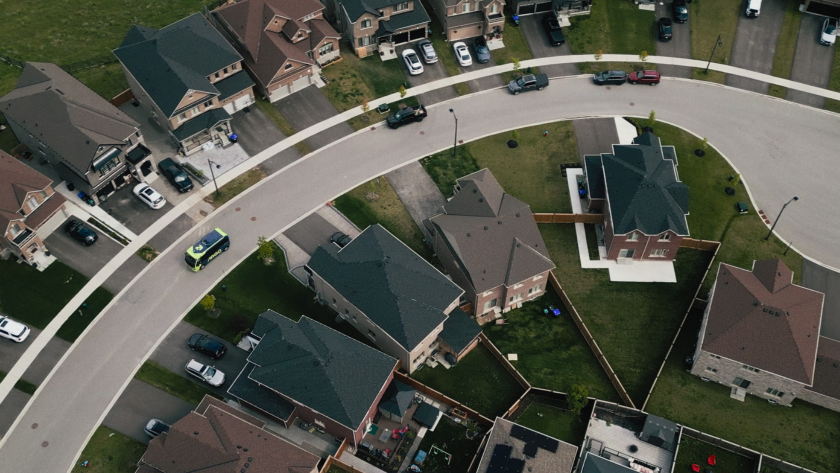 Overhead shot of the Ride Argo bus traveling along a curved street lined with houses.