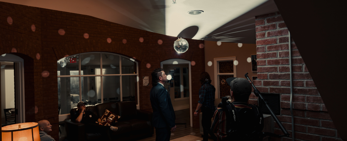 In a room with a ballroom light, the father, dressed in a suit, is preparing to dance with his leukemia patient daughter.