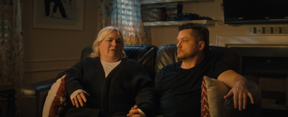 Parents of a leukemia patient seated on a couch, being interviewed.