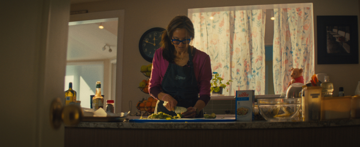 A lady cutting ingredients in the kitchen, preparing food.