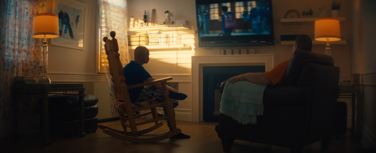 Two family members seated and watching television together.