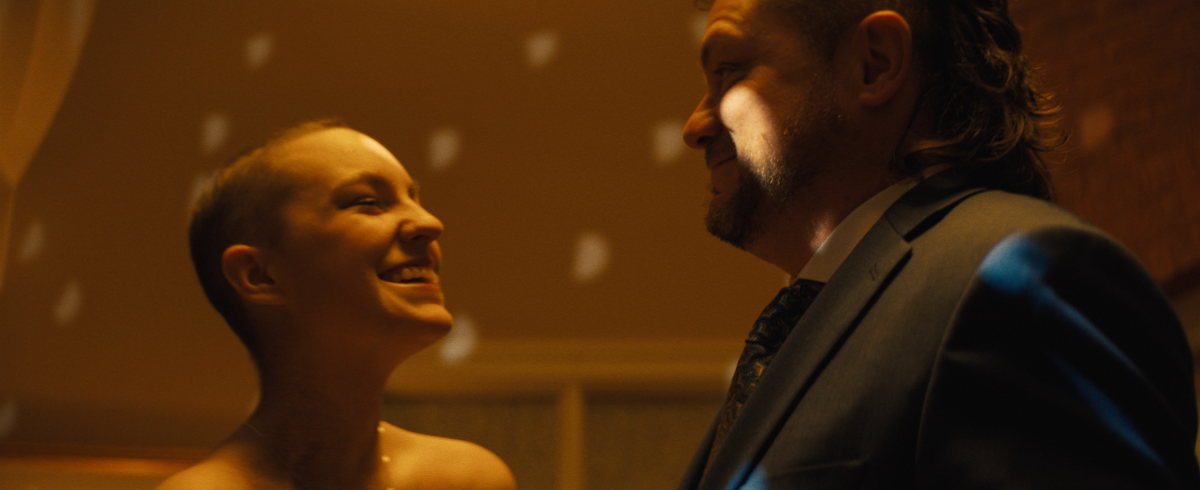 A close-up of the leukemia patient, wearing her prom dress, dancing happily with her dad.