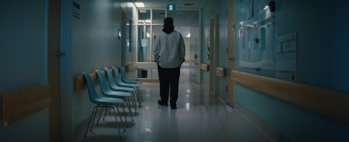 The father of a leukemia patient is walking and waiting in the hospital hallway.