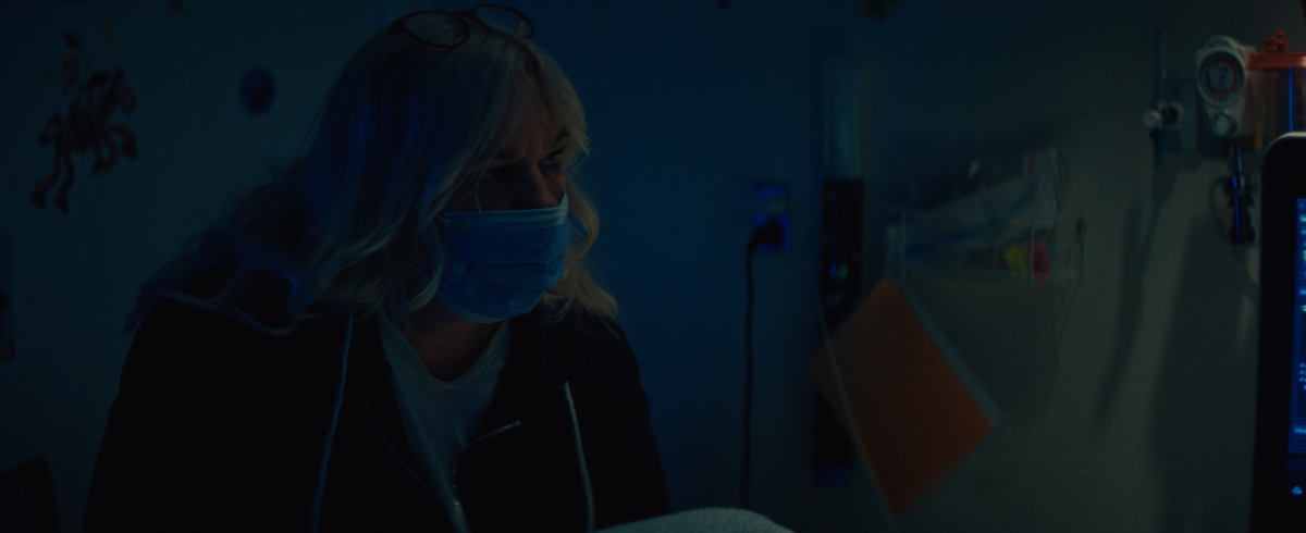 A mother of a leukemia patient is checking on her child while wearing a face mask.