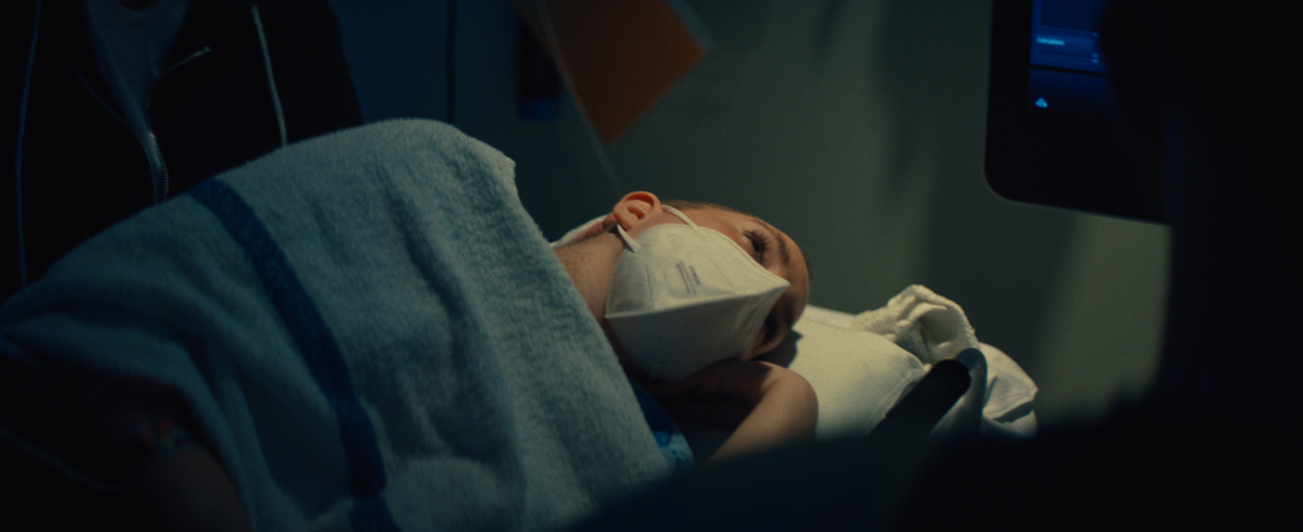 A leukemia patient lying in bed in the hospital, looking thoughtful and deep in thought.