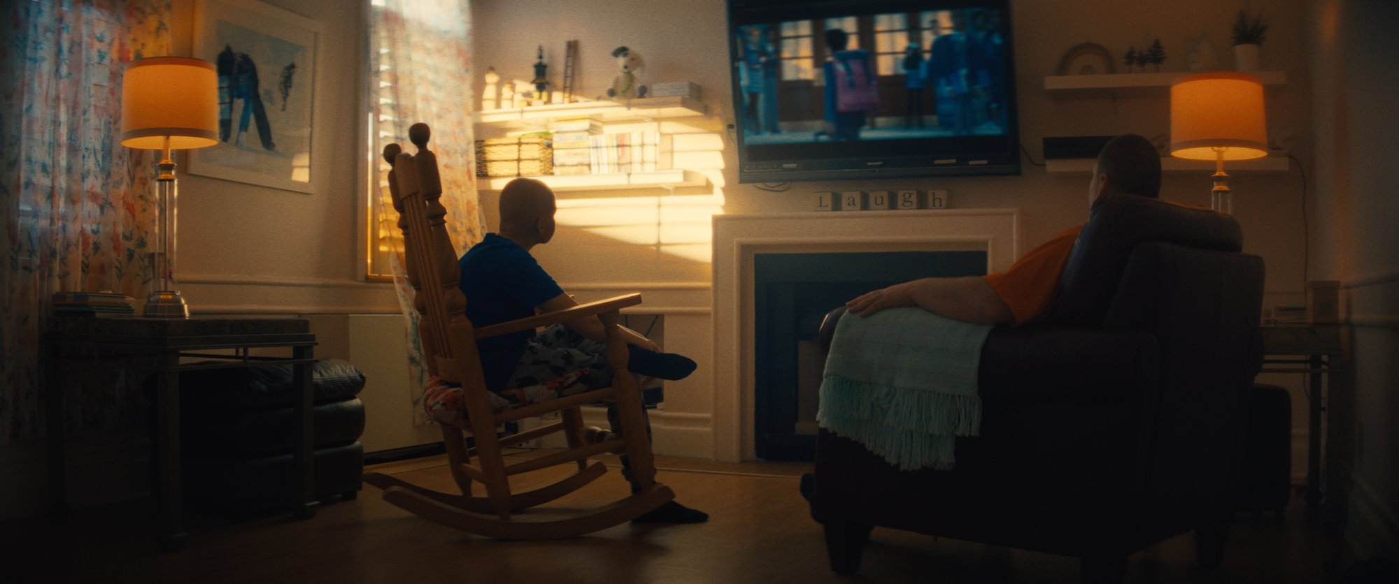 Two family members seated in front of the television watching together.