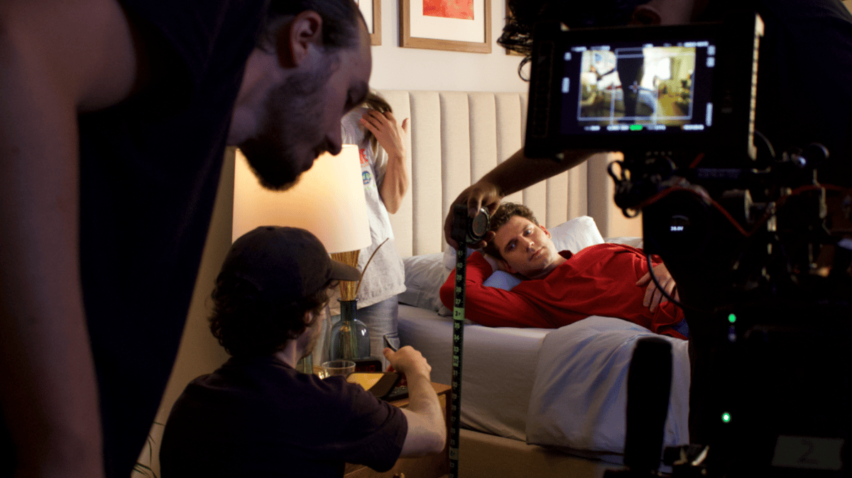 Production team setting up the set while the actor is in bed.